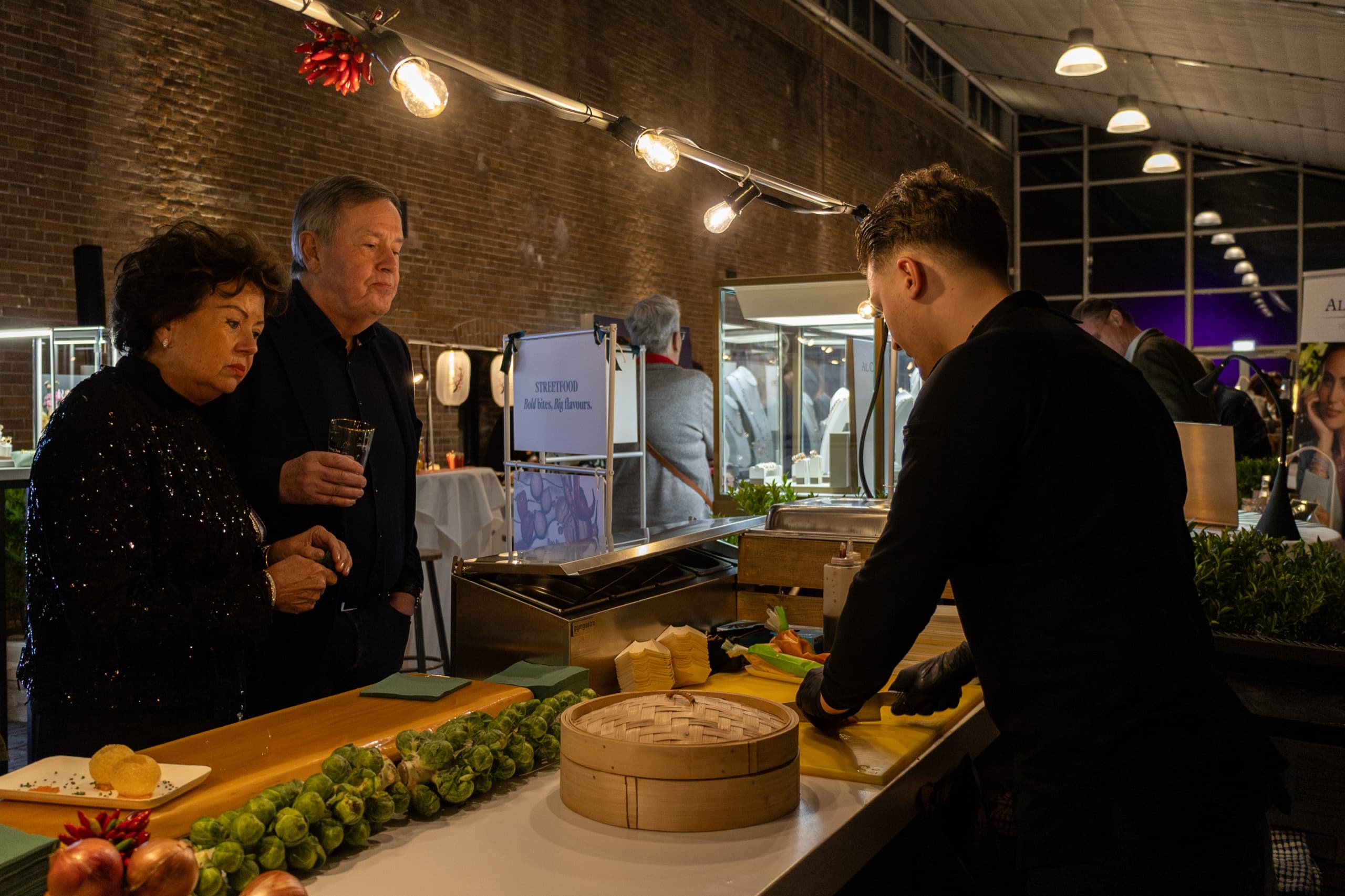Gasten kijken toe terwijl een chef streetfood bereidt aan de foodstand