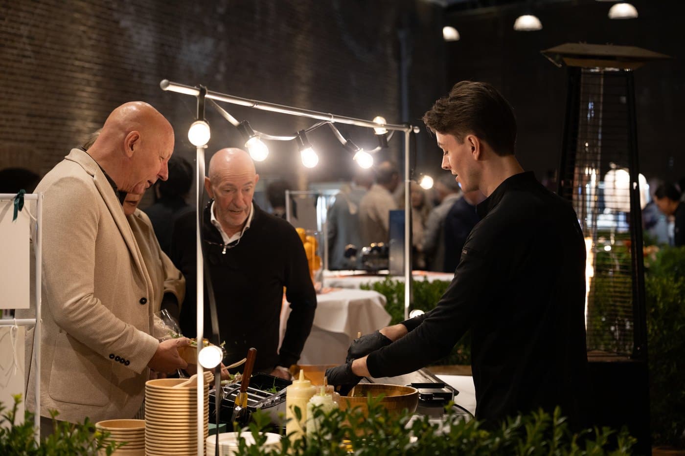 Gast krijgt een gerecht aangereikt bij een foodstand tijdens een avondevenement