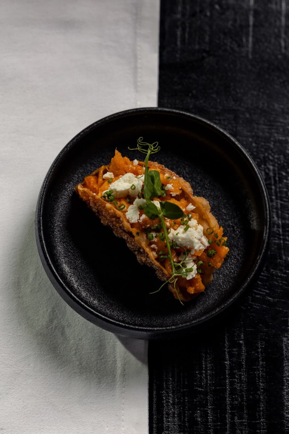 Sweet potato taco met feta en bieslook, geserveerd in een zwarte kom